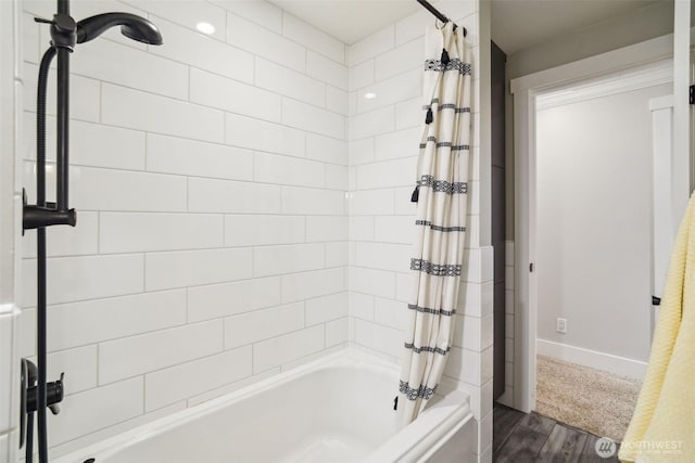 bathroom with wood finished floors, shower / bath combination with curtain, and baseboards