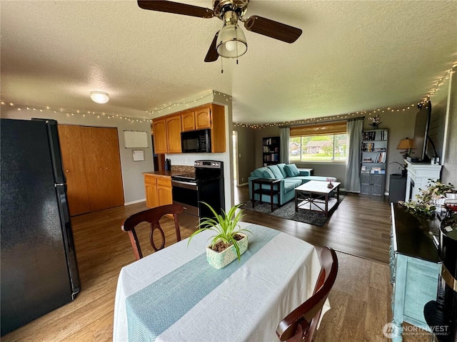 dining room with light wood-style floors, ceiling fan, and a textured ceiling
