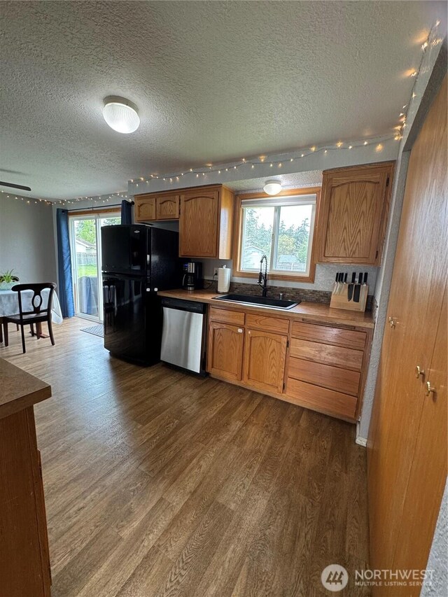 kitchen with dark wood finished floors, dishwasher, freestanding refrigerator, and a sink