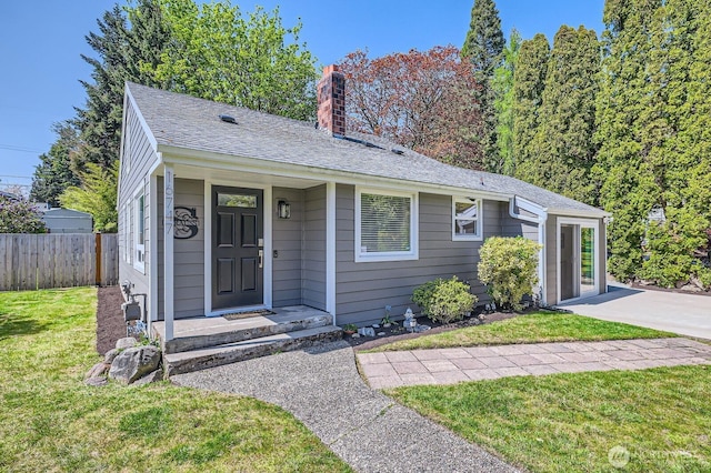 view of front of home with a chimney, fence, and a front lawn
