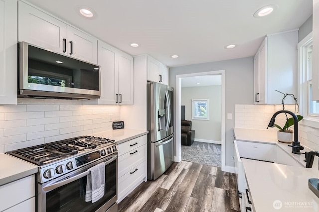 kitchen featuring dark wood-style floors, white cabinets, stainless steel appliances, and light countertops
