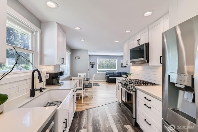 kitchen featuring dark wood-type flooring, white cabinets, appliances with stainless steel finishes, and light countertops