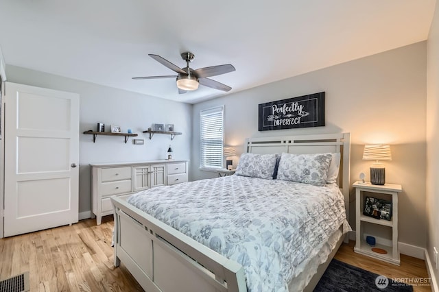 bedroom with light wood finished floors, visible vents, ceiling fan, and baseboards
