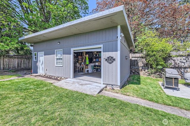 rear view of property featuring an outdoor structure, a yard, and a fenced backyard