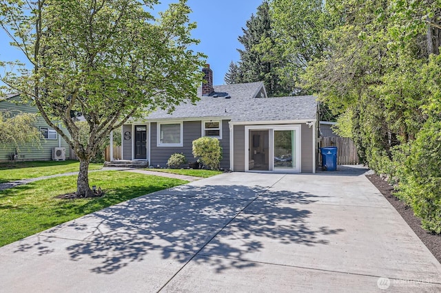 view of front of home with a front lawn, a chimney, roof with shingles, concrete driveway, and fence