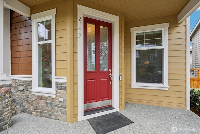 view of exterior entry featuring a porch and stone siding