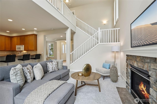 living room featuring recessed lighting, light carpet, stairway, and a fireplace
