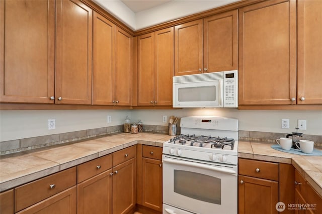 kitchen featuring white appliances, tile counters, and brown cabinetry