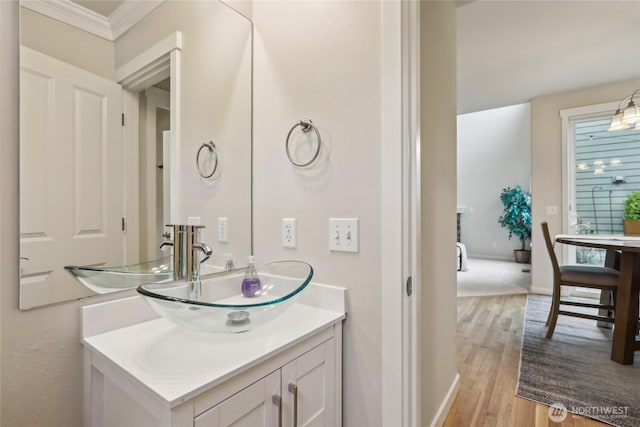 bathroom featuring crown molding, baseboards, wood finished floors, and vanity