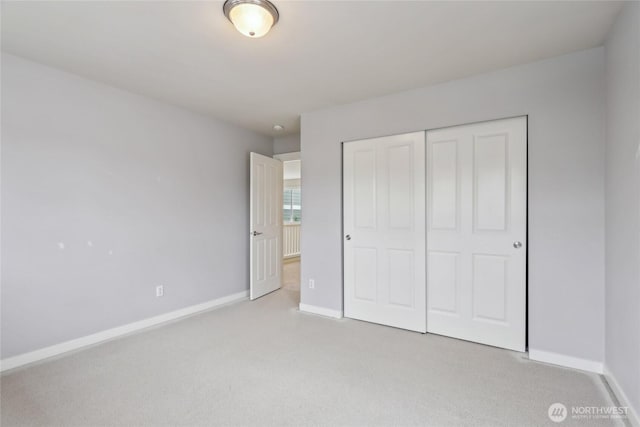 unfurnished bedroom with baseboards, a closet, and light carpet
