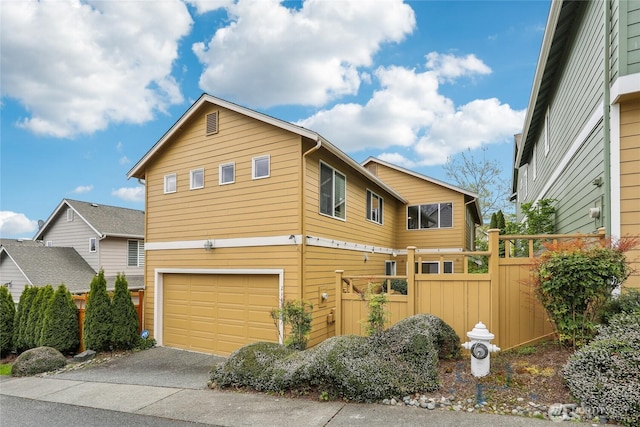 view of front of property featuring fence, an attached garage, and driveway