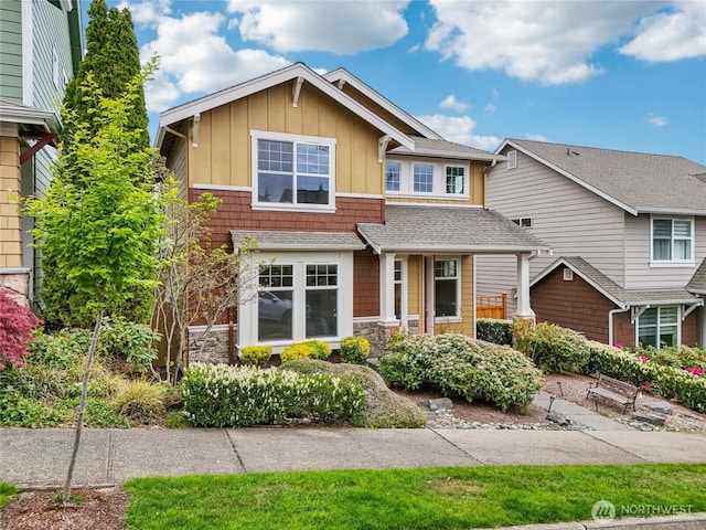 craftsman house featuring a shingled roof, board and batten siding, and stone siding