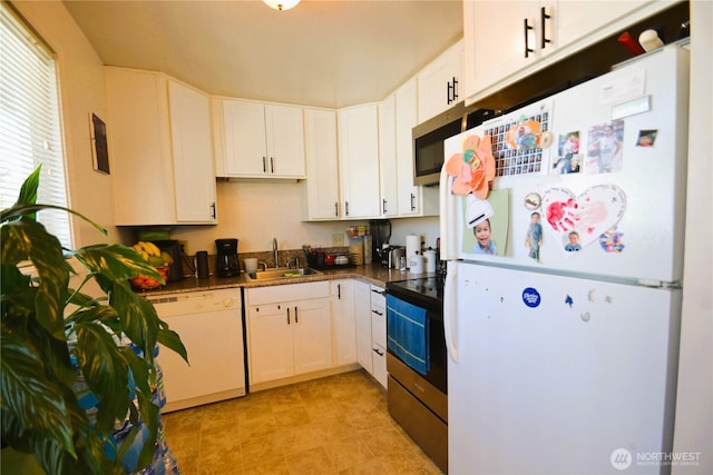 kitchen with dark countertops, white cabinetry, a sink, and white appliances