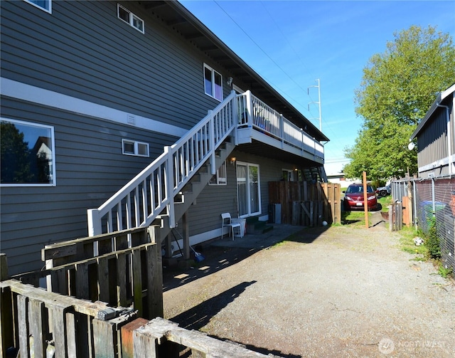 rear view of house featuring stairs, a deck, and fence
