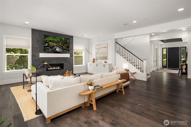 living room featuring dark wood-style flooring, a large fireplace, stairs, baseboards, and recessed lighting