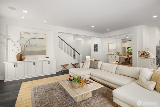 living area featuring recessed lighting, dark wood-style flooring, and stairs