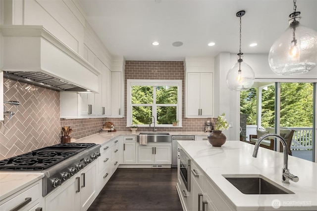 kitchen featuring appliances with stainless steel finishes, decorative backsplash, a sink, and premium range hood