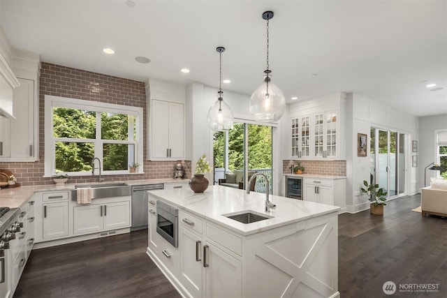 kitchen featuring a sink, appliances with stainless steel finishes, a healthy amount of sunlight, and tasteful backsplash