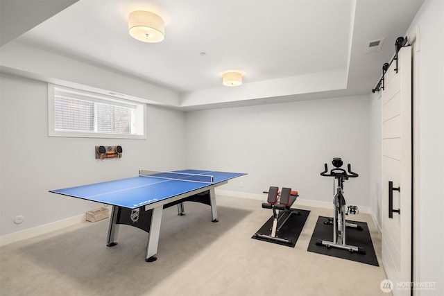 playroom with carpet floors, a barn door, a raised ceiling, and baseboards