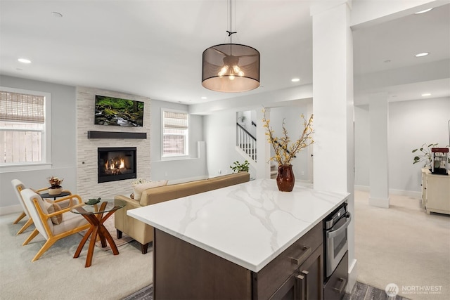 kitchen featuring a fireplace, dark brown cabinets, light carpet, stainless steel oven, and recessed lighting