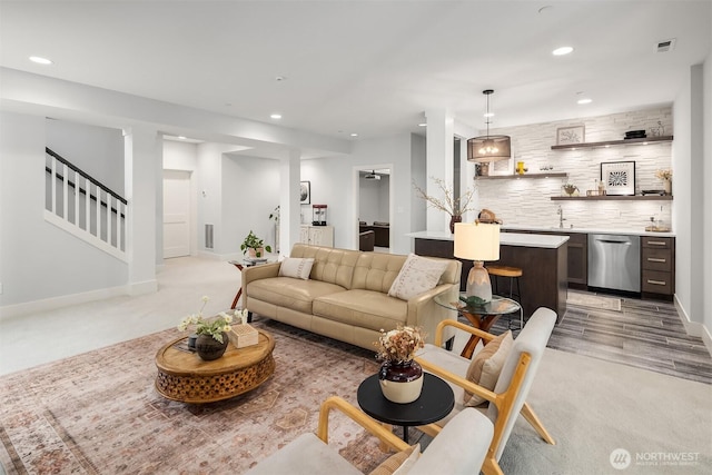 living area featuring visible vents, light colored carpet, recessed lighting, and stairs