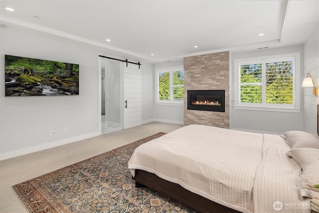 bedroom featuring recessed lighting, baseboards, a barn door, and a fireplace