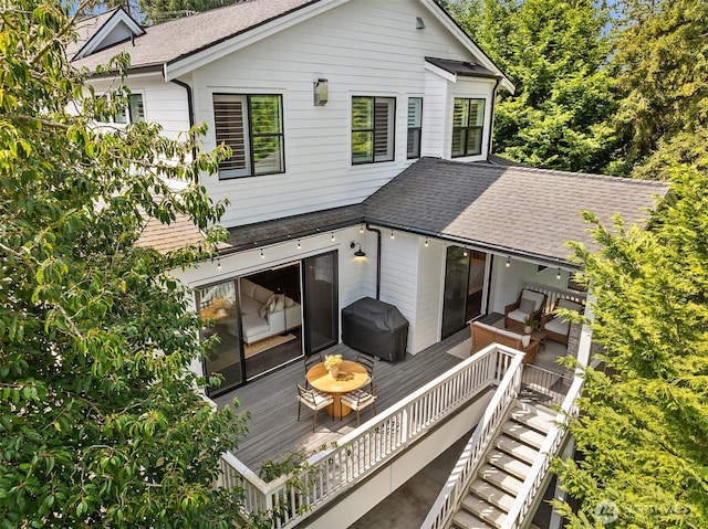 back of house featuring stairway, a deck, and a shingled roof
