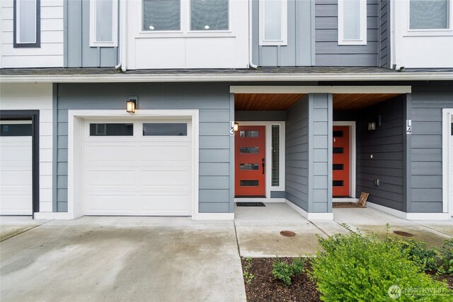 doorway to property with board and batten siding, driveway, covered porch, and a garage