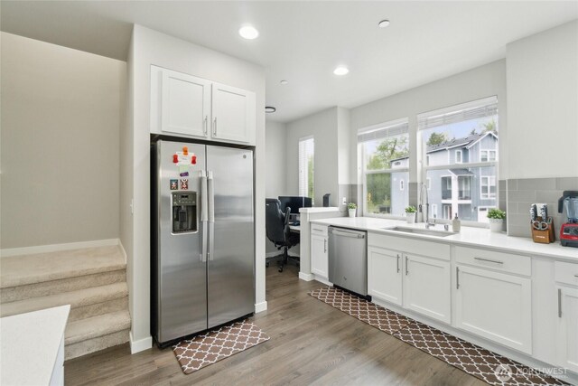 kitchen featuring white cabinets, appliances with stainless steel finishes, a sink, recessed lighting, and light wood-type flooring