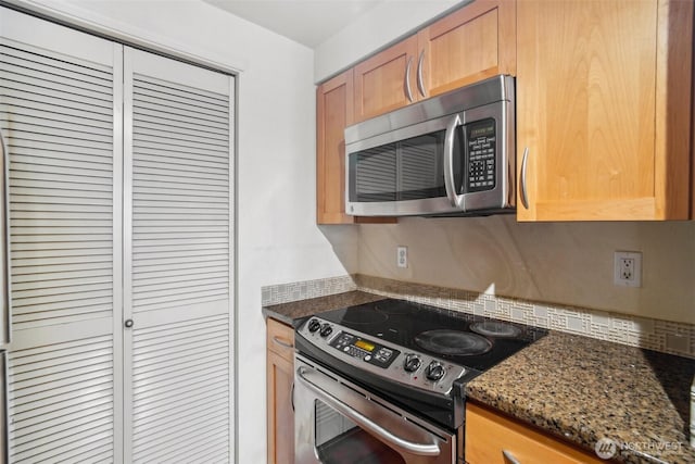 kitchen featuring appliances with stainless steel finishes, dark stone counters, and tasteful backsplash