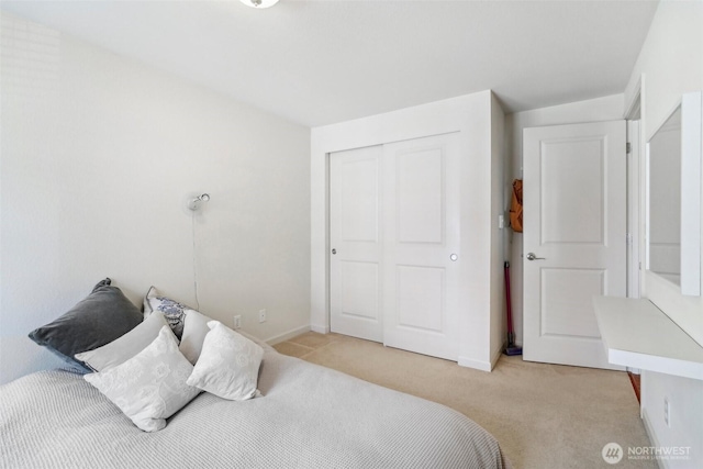 bedroom with light colored carpet, baseboards, and a closet