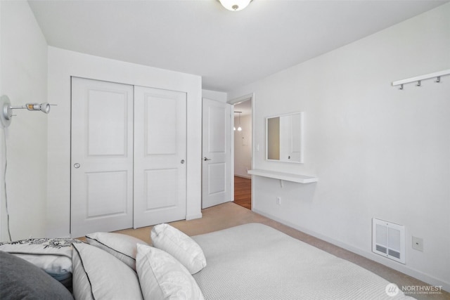 carpeted bedroom featuring baseboards, visible vents, and a closet