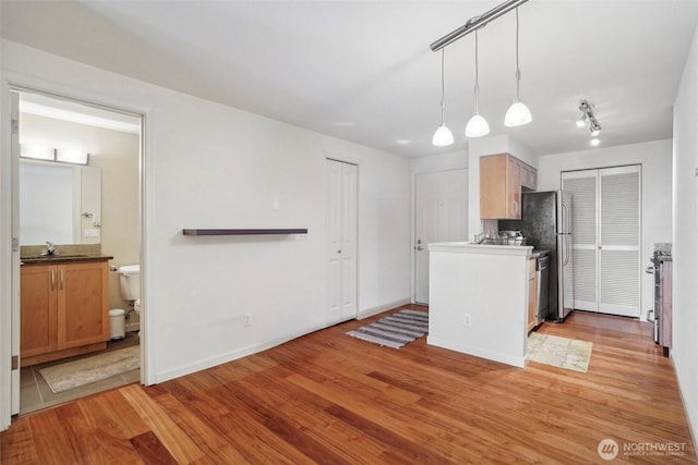 3045 20th Ave W Unit 208, Seattle, WA 98199 - kitchen featuring light wood-style flooring, a sink, baseboards, and hanging light fixtures