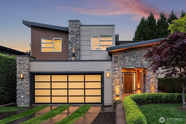 contemporary house with a garage, driveway, and stone siding