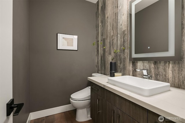 bathroom with baseboards, wood finished floors, toilet, and vanity