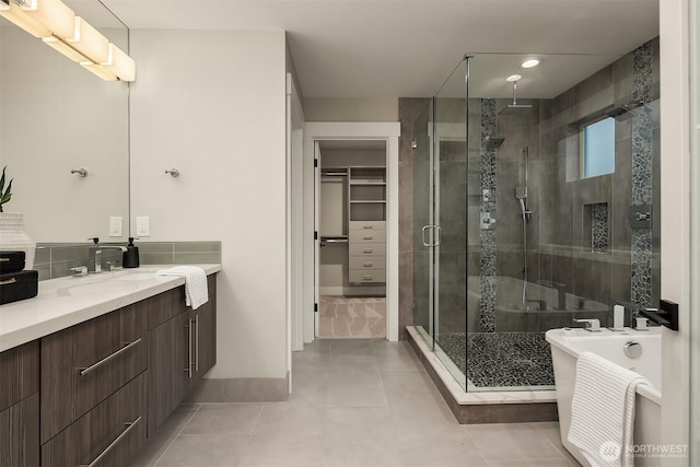 bathroom with vanity, a walk in closet, tile patterned floors, a soaking tub, and a stall shower