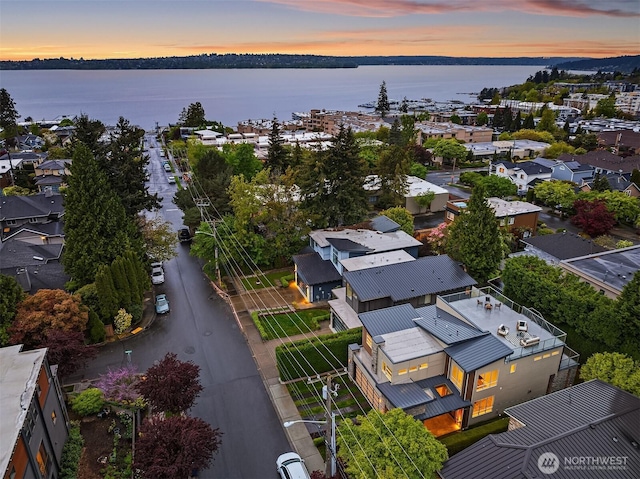 aerial view at dusk featuring a water view