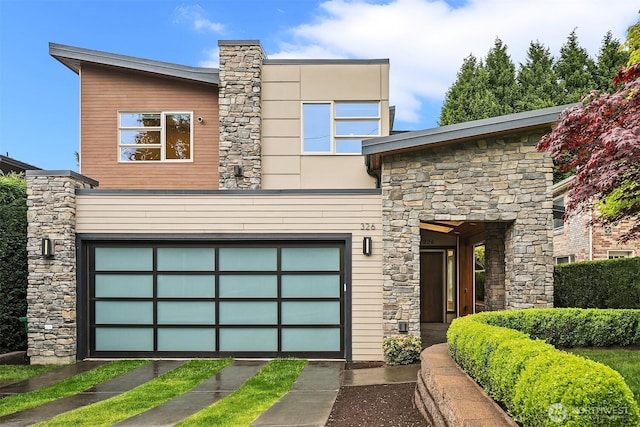 modern home with an attached garage, driveway, and stone siding