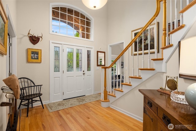 foyer featuring baseboards, wood finished floors, stairway, and a towering ceiling