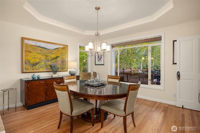 dining area featuring an inviting chandelier, crown molding, baseboards, light wood-type flooring, and a tray ceiling