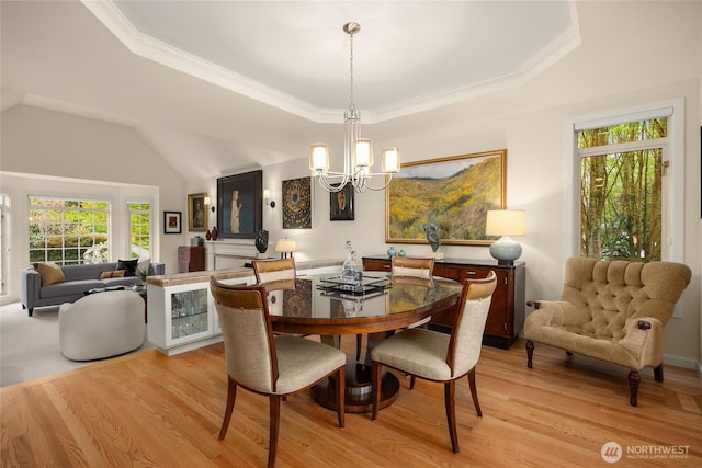 dining room with light wood-style floors, crown molding, a tray ceiling, and a notable chandelier