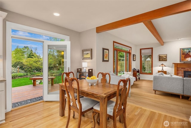 dining room with beamed ceiling, a healthy amount of sunlight, and light wood finished floors
