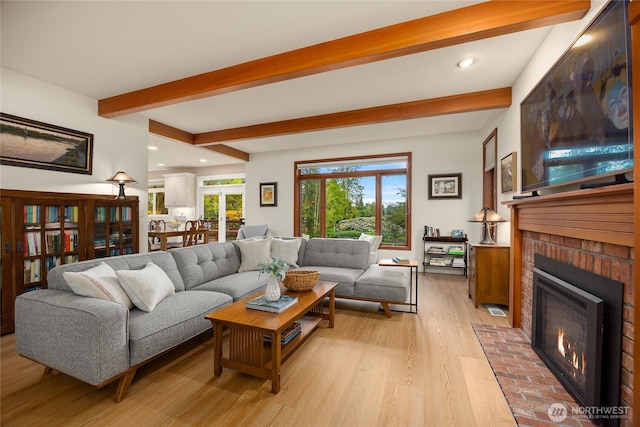 living room with a brick fireplace, recessed lighting, beamed ceiling, and light wood-style flooring