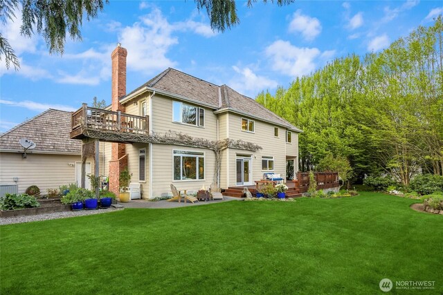 rear view of property with a patio, a chimney, a yard, and a deck