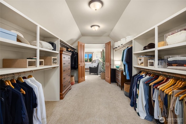 walk in closet with vaulted ceiling and light carpet
