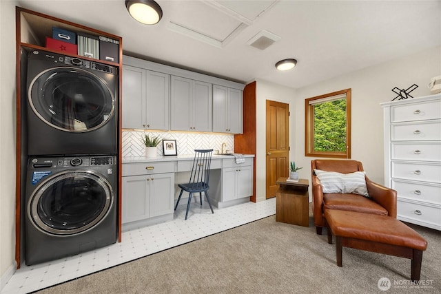washroom with laundry area, attic access, stacked washer and dryer, a sink, and light carpet