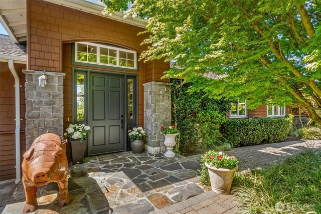property entrance with a shingled roof and stone siding
