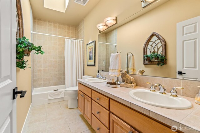 full bath with toilet, shower / bath combination with curtain, a sink, and tile patterned flooring