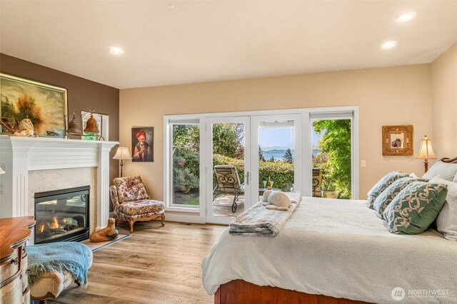 bedroom featuring a fireplace, recessed lighting, wood finished floors, and access to exterior