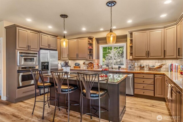 kitchen with a sink, light wood-style floors, open shelves, and a kitchen bar